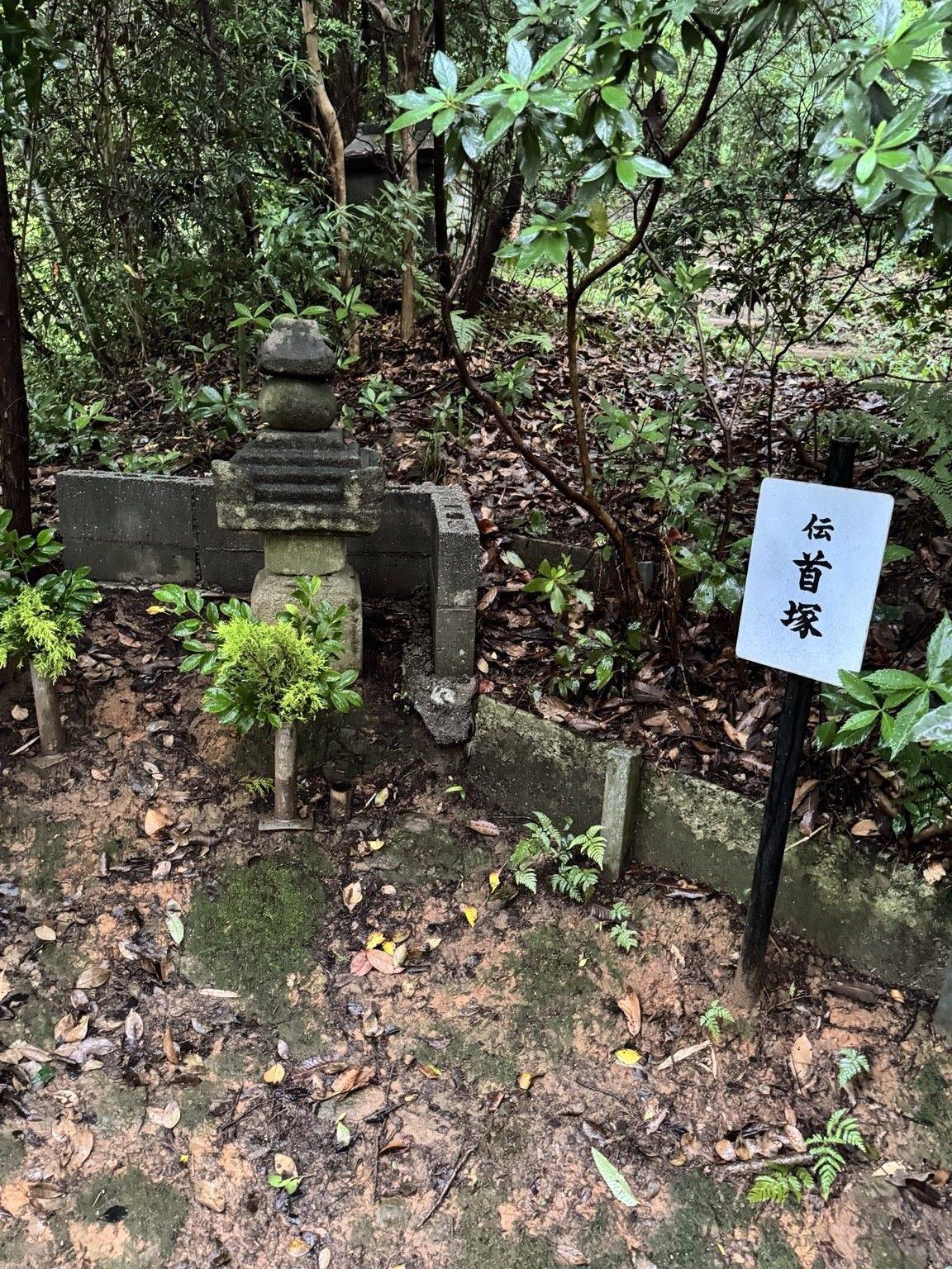 A stone structure and a sign reading 伝首塚 at Tōkō-ji in Nishio