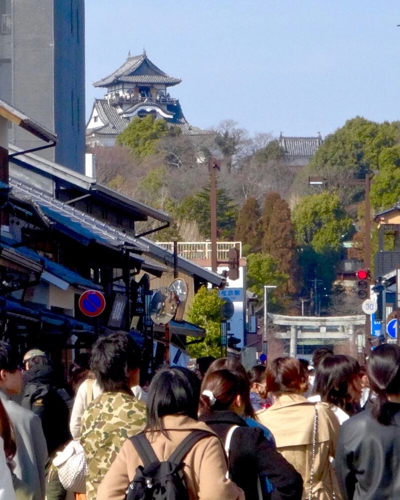 A busy castle-town street in Inuyama with the castle keep on the hill beyond